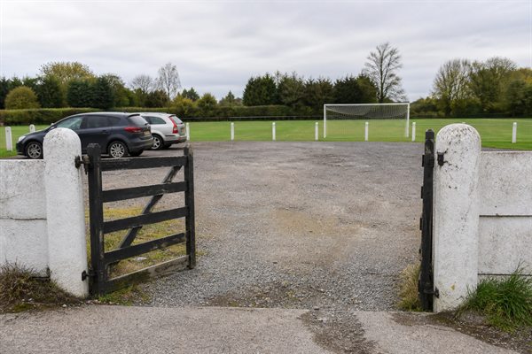 Illustrative photo of the car-park entrance, with a football pitch beyond the gate